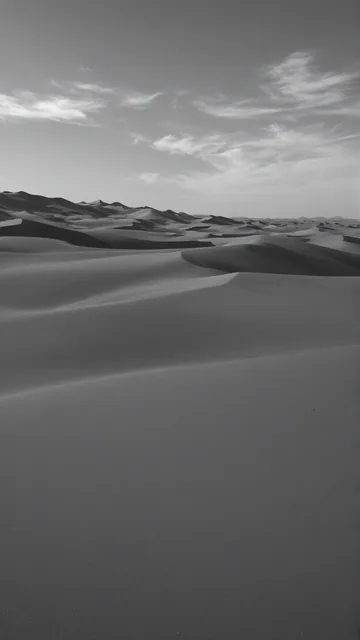 Dunas desérticas con sombras suaves y cielo nublado